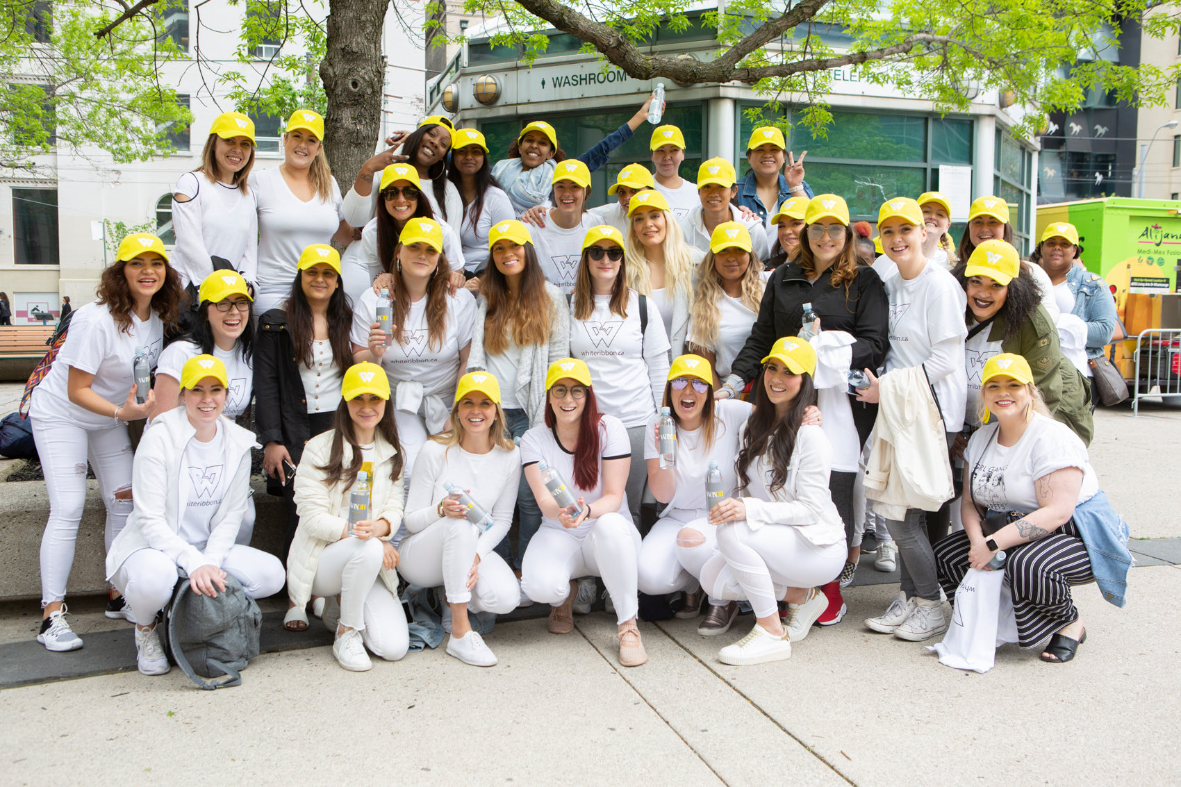 WAXON Laser and Wax Bar team outside celebrating. All staff are wearing white outfits with yellow hats in the WAXON Brand colours.