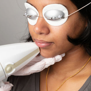 Woman receiving laser hair removal on her face. Client is wearing protective eye wear